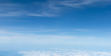 Beautiful landscape view trough window of airplane and cloudless sundown sky behind window of aircraft during flight. blue sky. Flying in the sky and the sea of clouds.