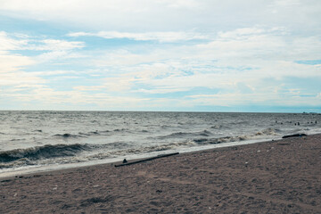Serene beach landscape, gentle waves lapping at sandy shore under a cloudy sky, perfect for relaxation and reflection.