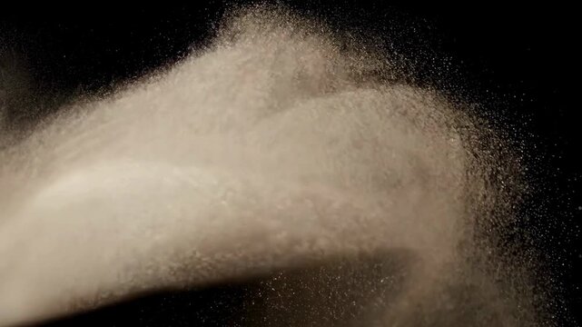A high-speed video of fine, white sand or dust particles swirling and cascading from left to right against a black background, perfect for cinematic or artistic overlays