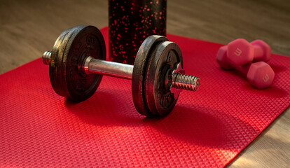 Close up of heavy metal dumbbell on red fitness mat and other sport equipment 