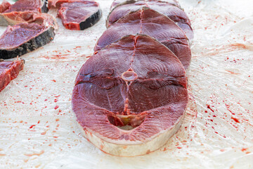 Fresh tuna steaks displayed at fish market, raw red meat cuts ready for cooking, seafood preparation for restaurant kitchen or home cooking