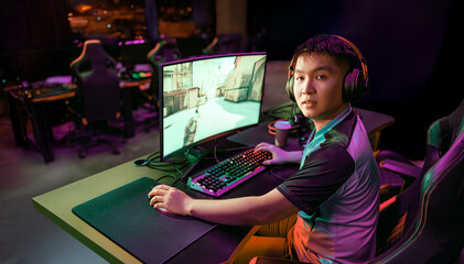 A young gamer is deeply immersed in a highperformance gaming setup in an energetic esports environment