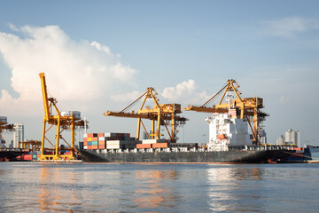 Obraz premium Activity of modern seaport in Bangkok of Thailand. Cargo ship loaded with containers docked alongside towering cranes, under bright sky. Business industry of shipping, logistics and import export.