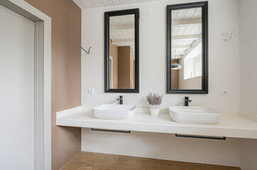 Modern bathroom with two square sinks, black framed mirrors, and a clean white countertop. The textured white wall and wood-look flooring adds style