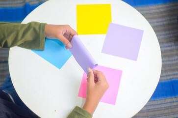 Child's hands folding origami paper on the table. 
