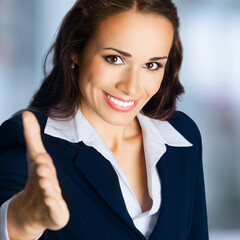 Happy smile beautiful cute black hair businesswoman, business woman, office worker, bank employee, hr manager, lawyer giving hand for handshake, stand against blurred office background. Square image