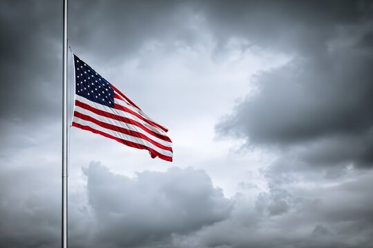 United States flag flies at half mast against a cloudy sky.