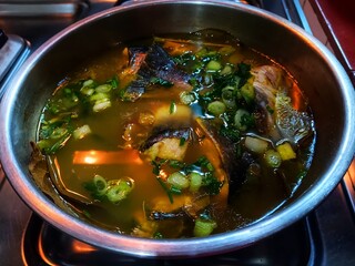 Silver catfish in yellow soup cooked in a stainless steel bowl.