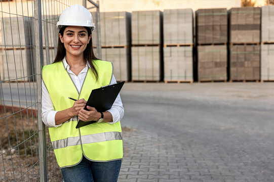 young woman architect wearing safety vest helmet holding tablet smiling construction site mujer joven arquitecta con chaleco de seguridad y casco sosteniendo una tableta y sonriendo
