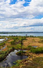 A picturesque landscape with a power line next to a lake and a beautiful cloudy sky