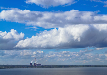 Industrial power plant by lake under blue sky