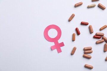 Menopause. Female gender symbol and pills on light background, flat lay. Space for text