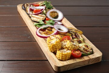 Vegetarian barbecue. Tasty grilled vegetables and parsley on wooden table, closeup
