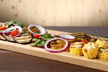 Vegetarian barbecue. Tasty grilled vegetables and parsley on wooden table, closeup