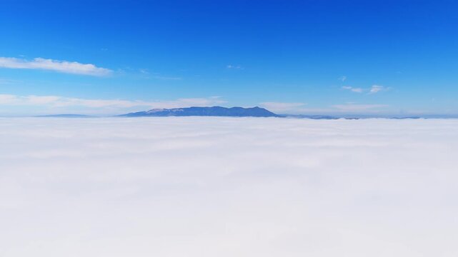 An aerial view shows a vast layer of white clouds with a mountain range visible above. The camera moves forward, focusing on the serene horizon over San Francisco in California.