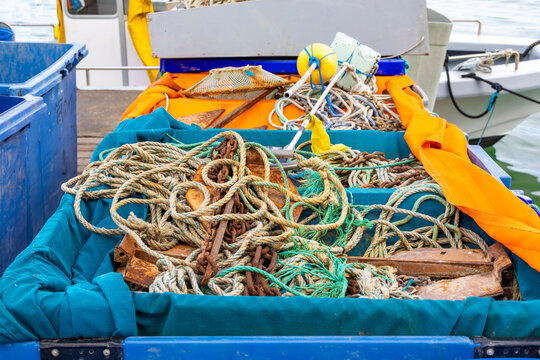 Fishing boat with tangled ropes and equipment in blue containers, commercial fishing vessel gear ready for next sea voyage at harbor dock - Powered by Adobe