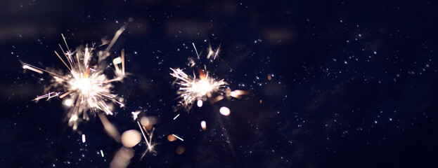 Dark night sky with glowing sparklers and golden bokeh. Horizontal background for christmas and new...