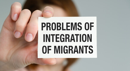 A hand holding a white card with the words Problems of Integration of Migrants written on it