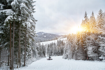 Snow groomer actively shaping a ski slope.