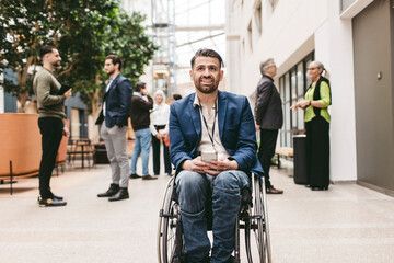 Male business expert sitting on wheelchair looking away in convention center