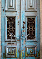 A weathered blue door is secured with a chain and padlock.