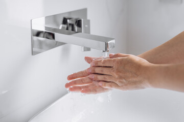 Close-up of hands being washed under running water with soap, highlighting hygiene, purity and responsible water consumption. Concept of cleanliness, health protection, eco awareness and sustainable l