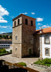 A stone church tower with bells under a blue sky.