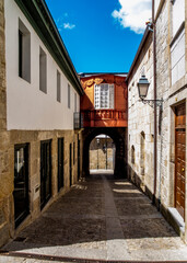 Fototapeta premium A narrow street in a historic town with a wooden bridge connecting buildings.
