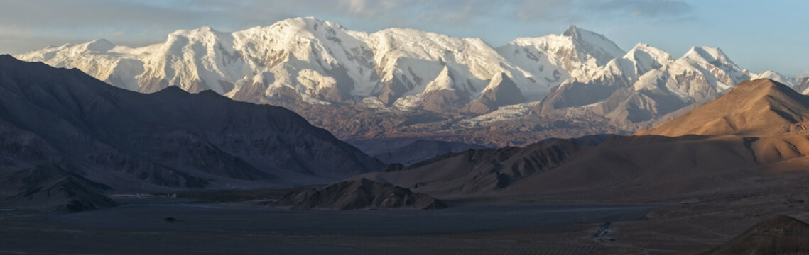 Aerial view of the majestic Muztagh Ata mountain range, its snow-capped peaks gleaming against the stark, arid landscape, Muztagh Glacier, China.