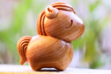 A wooden horse sits atop a table, perfect for decorative use or as a prop in photography shoots