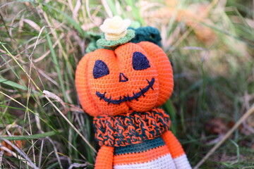A cozy and autumnal scene featuring a handmade, crocheted pumpkin sitting in the grass