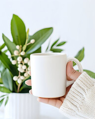 Cozy hands cradle a clean white mug surrounded by lush greenery, evoking warmth and tranquility for your lifestyle brand.