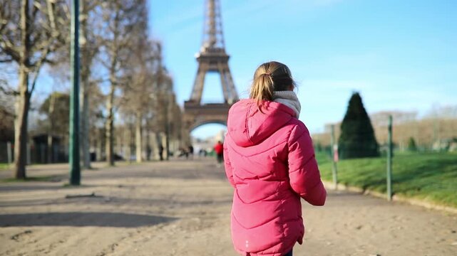 girl in pink jacket near the Eiffel Tower in winter