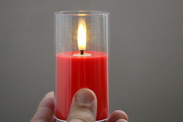 A person holding a lit candle for warmth or light
