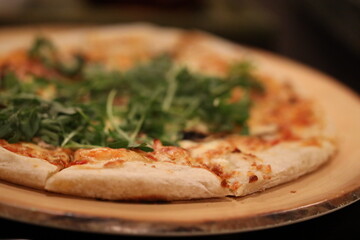 Freshly baked pizza topped with mixed greens and served on a plate