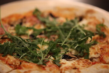 Freshly made pizza with leafy greens on a crisp white plate, ready to be devoured