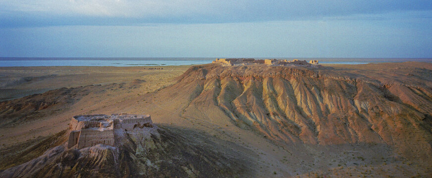 Aerial view of Ayaz Kala fortress ruins stand against the vast desert landscape, with the distant shimmer of the sea, Ayaz Kala, Republic of Karakalpakstan, Uzbekistan.