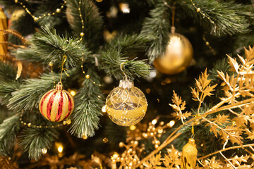 close up golden multicolor decoration ball with snow star and light bulb on Christmas tree pile tree at night time on holiday snowy xmas theme in december 