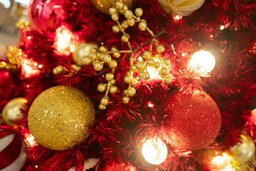 Close up red Christmas tree with red golden ball ornament and gold leaf decoration with light bulb