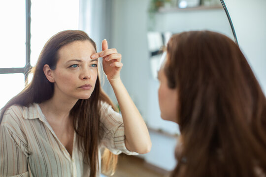 Woman applying skincare in front of mirror