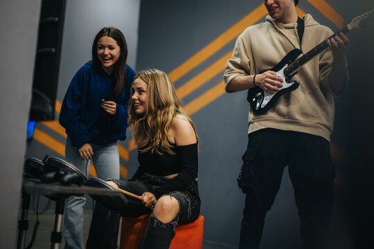 Friends engaging in entertainment activities, playing musical video games with a guitar, drumsticks, and microphone. The atmosphere is casual and filled with fun and laughter.