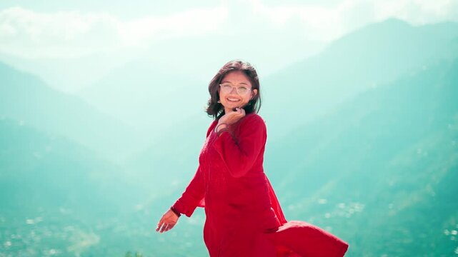 4K Portrait of beautiful young woman wearing red color salwar suite standing in mountains at Manali, Himachal Pradesh, India. Traditional Indian clothes. Confident and independent Indian woman.