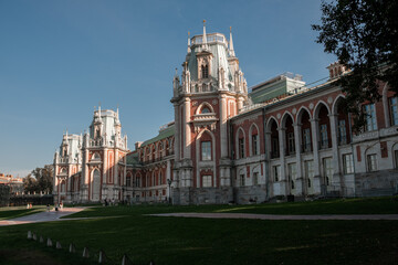 Obraz premium Visitors enjoy the serene beauty of Tsaritsyno park, admiring its impressive buildings and lush greenery under a bright blue sky