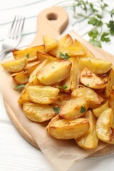 Tasty baked potatoes with parsley on white wooden table, closeup