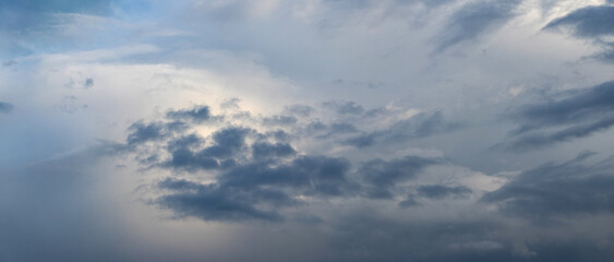 A gray stormy sky partially illuminated by sunlight, creating a dramatic effect of changing weather