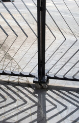 Abstract shadow pattern of metal grid cast on beige wall by sunlight.