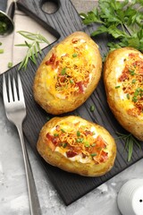 Tasty stuffed baked potatoes served on grey textured table, flat lay