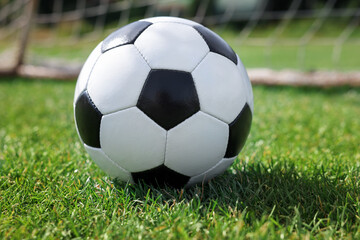 Fototapeta premium Soccer ball on green grass outdoors, closeup. Football game