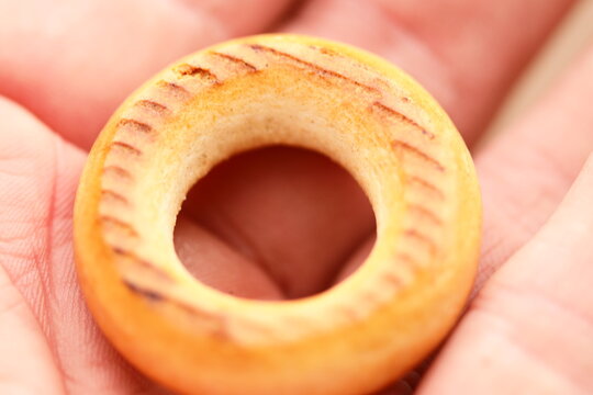 A person holds a wooden donut in their hand, perfect for a foodie or bakery theme
