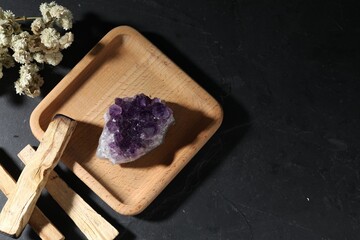 Beautiful amethyst gemstone, palo santo and dried flowers on black table, flat lay. Space for text